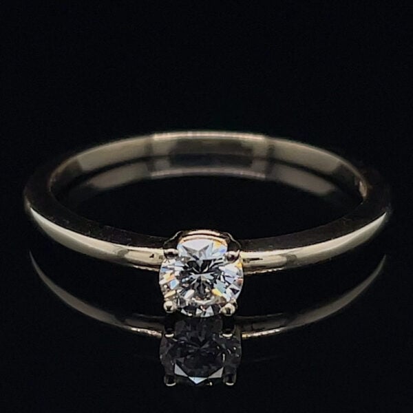 Diamond solitaire ring on a silver band, displayed on a black reflective surface.