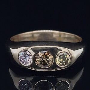 Silver ring with three evenly spaced round-cut gems—blue left, champagne center, pale yellow right—on a dark background.