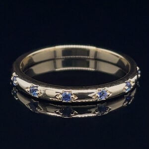 Silver ring with small blue gemstones set evenly around the band.