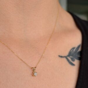 Delicate gold chain necklace with a small diamond pendant resting on the collarbone area.