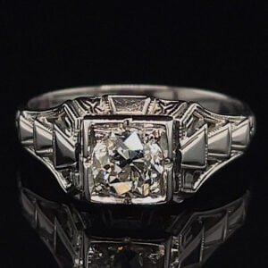 Ring featuring a large square-cut diamond center with angular, step-like shoulders on a dark backdrop