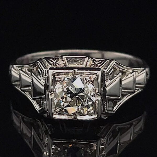 Ring featuring a large square-cut diamond center with angular, step-like shoulders on a dark backdrop