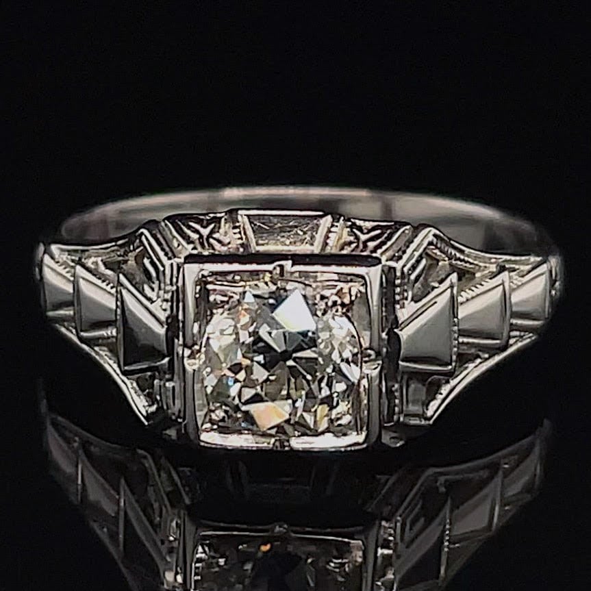 Ring featuring a large square-cut diamond center with angular, step-like shoulders on a dark backdrop
